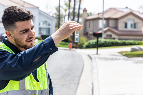 Water quality staff collecting a water sample in a residential area.