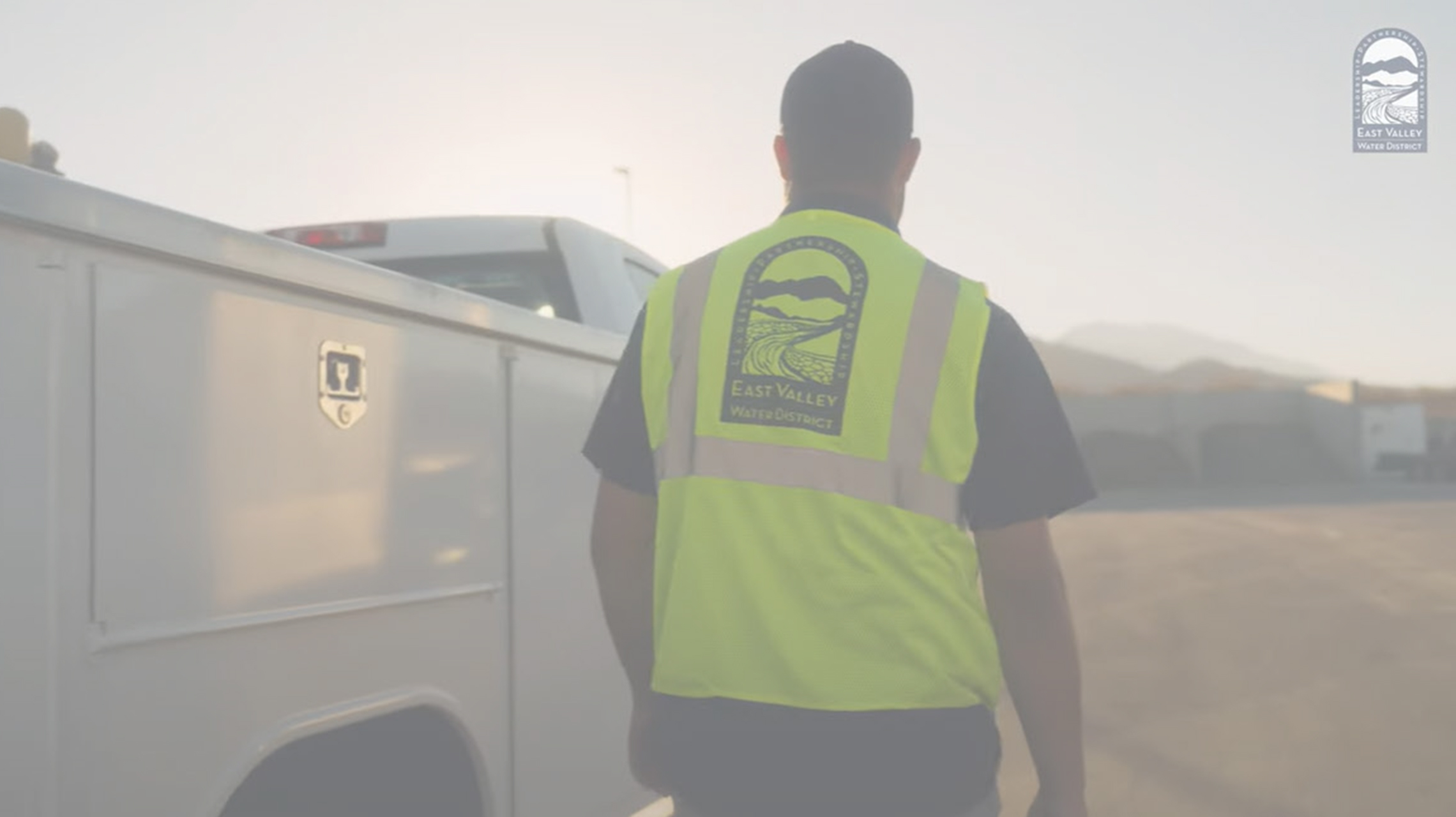Image of Who We Are Video Thumbnail showing a staff member wearing a vest and a work truck, click to open modal window with video